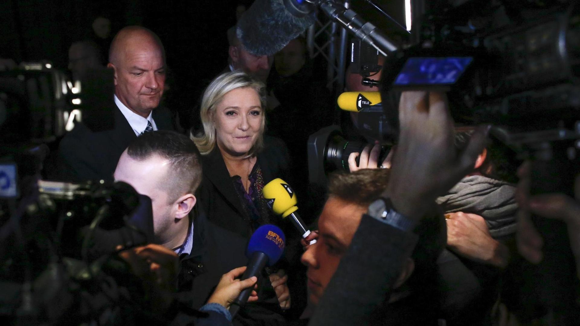 Marine Le Pen umringt von Kameras und Mikrofonen. Marine Le Pen umringt von Kameras und Mikrofonen.