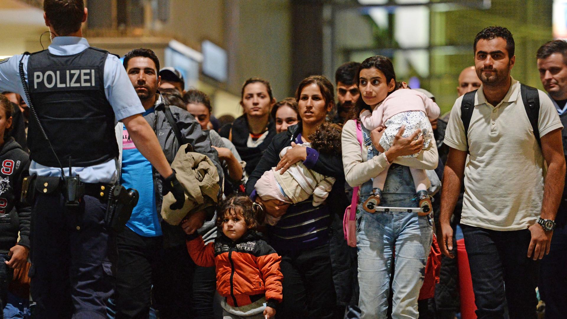 Flüchtlinge, darunter viele Frauen und Kinder, kommen am Hauptbahnhof in München an und gehen von Polizisten begleitet durch den Bahnhof. Flüchtlinge, darunter viele Frauen und Kinder, kommen am Hauptbahnhof in München an und gehen von Polizisten begleitet durch den Bahnhof.