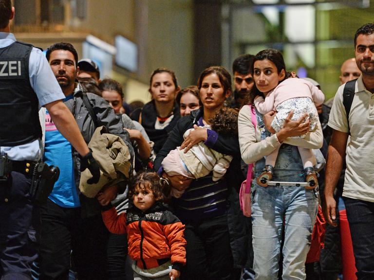 Flüchtlinge, darunter viele Frauen und Kinder, kommen am Hauptbahnhof in München an und gehen von Polizisten begleitet durch den Bahnhof.