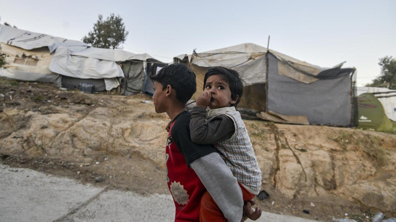 Ein Flüchtlingsjunge trägt im Lager Moria in Griechenland seinen kleinen Bruder auf dem Rücken.