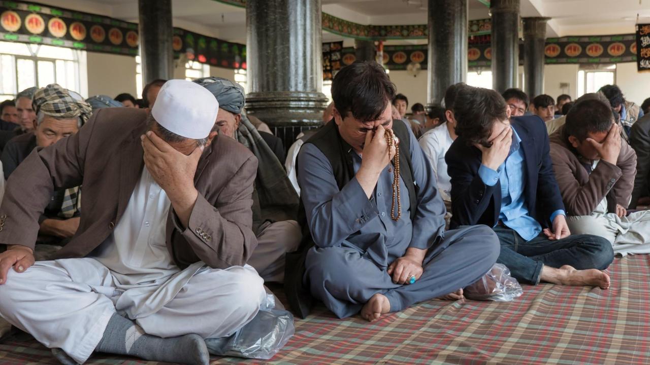 Schluchzende Männer sitzen in der Kabuler Daimirdadiha-Moschee Schluchzende Männer sitzen in der Kabuler Daimirdadiha-Moschee