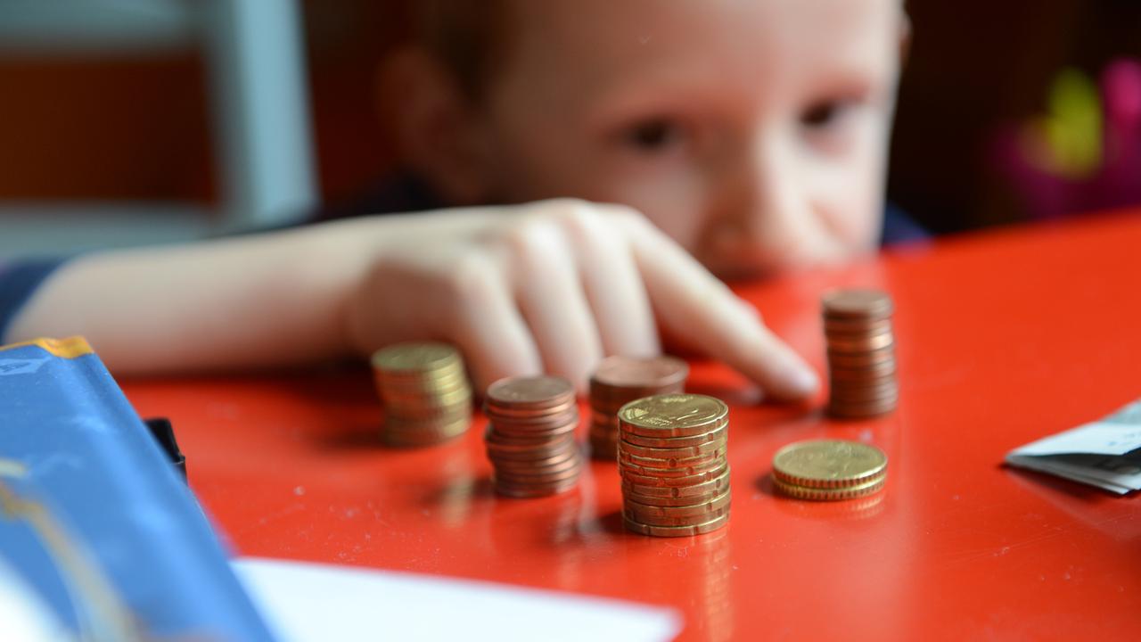 Ein fünfjähriger Junge sitzt an einem roten Tisch und zählt sein gespartes Taschengeld Ein fünfjähriger Junge sitzt an einem roten Tisch und zählt sein gespartes Taschengeld