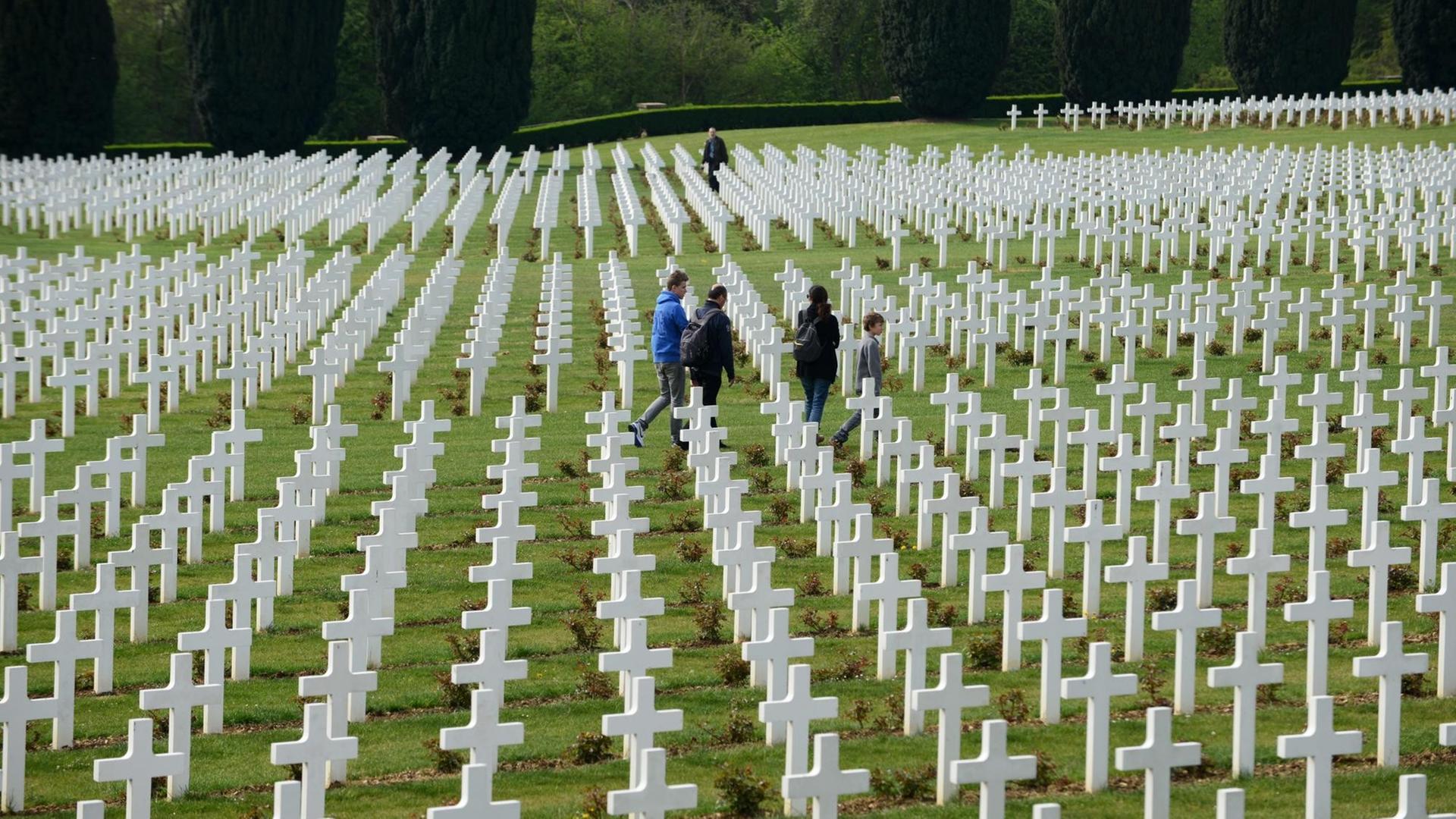 Besucher gehen zwischen den Grabkreuzen auf dem französischen Soldatenfriedhof am Beinhaus von Douaumont (Hintergrund) aus dem Ersten Weltkrieg nahe Verdun/Frankreich (Region Lorraine), aufgenommen am 25.04.2014. Besucher gehen zwischen den Grabkreuzen auf dem französischen Soldatenfriedhof am Beinhaus von Douaumont (Hintergrund) aus dem Ersten Weltkrieg nahe Verdun/Frankreich (Region Lorraine), aufgenommen am 25.04.2014.