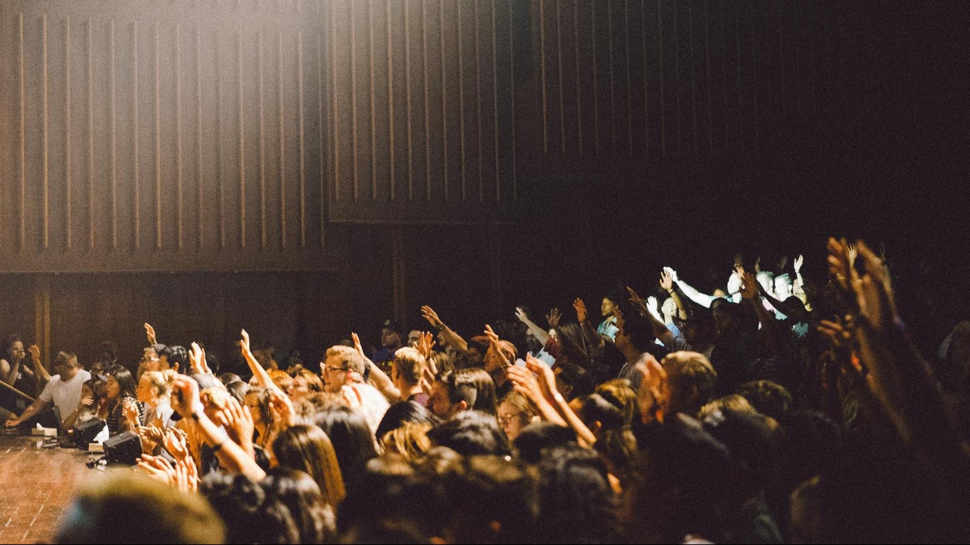 Schüler sitzen in der Aula und stimmen mit den Händen ab. Schüler sitzen in der Aula und stimmen mit den Händen ab.