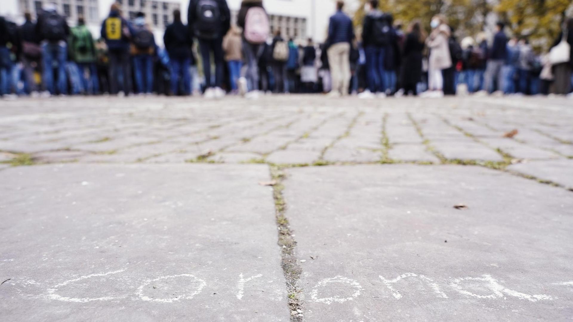 Erstsemester-Studenten stehen bei einer Willkommensveranstaltung auf dem Universitätsplatz vor dem Gebäude der Neuen Universität hinter dem mit Kreide auf dem Boden aufgemalten Schriftzug "corona" Erstsemester-Studenten stehen bei einer Willkommensveranstaltung auf dem Universitätsplatz vor dem Gebäude der Neuen Universität hinter dem mit Kreide auf dem Boden aufgemalten Schriftzug "corona"