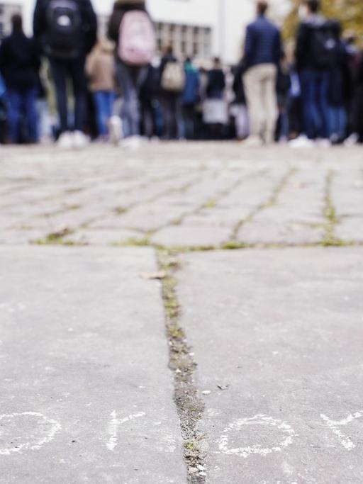 Erstsemester-Studenten stehen bei einer Willkommensveranstaltung auf dem Universitätsplatz vor dem Gebäude der Neuen Universität hinter dem mit Kreide auf dem Boden aufgemalten Schriftzug "corona"