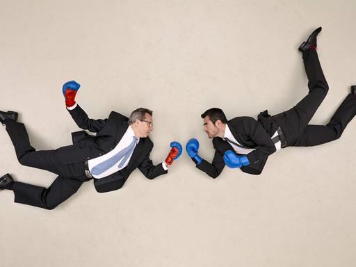Zwei Geschäftsmänner in fliegender Pose und mit Boxhandschuhen