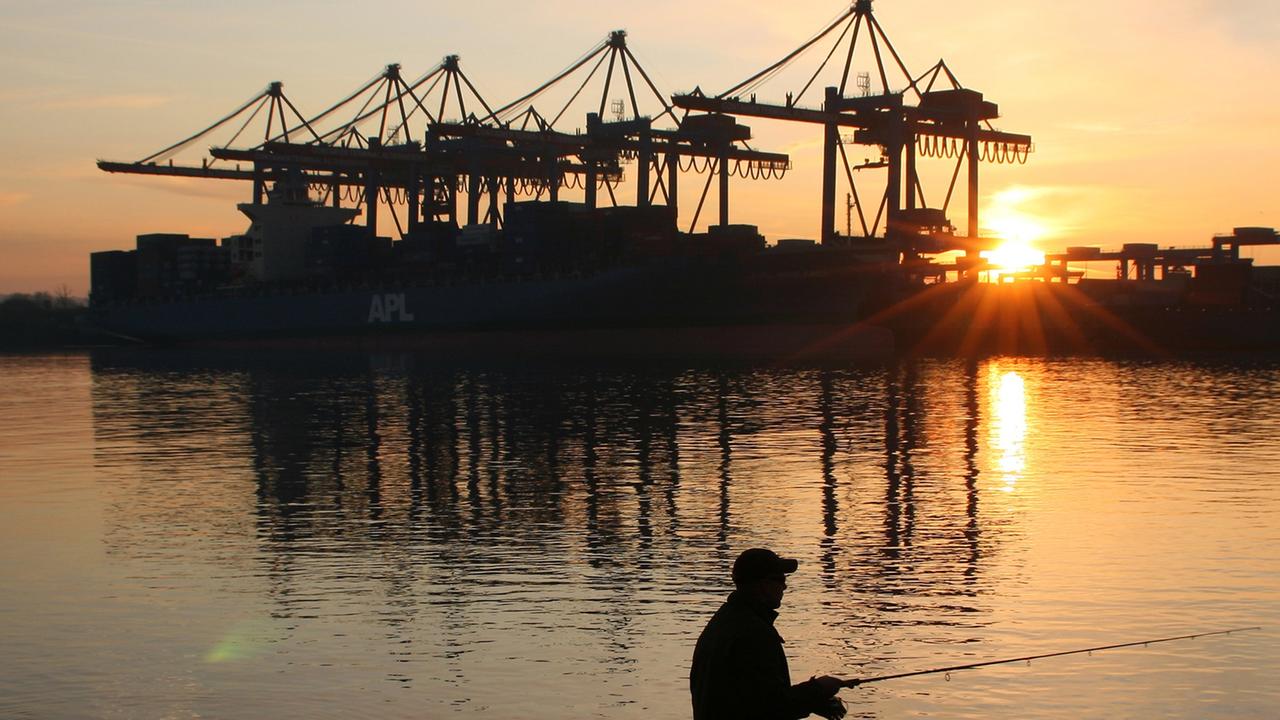 Ein Mann angelt am während des Sonnenuntergangs vor dem Container-Terminal Altenwerder (CTA) im Hamburger Hafen. Ein Mann angelt am während des Sonnenuntergangs vor dem Container-Terminal Altenwerder (CTA) im Hamburger Hafen.