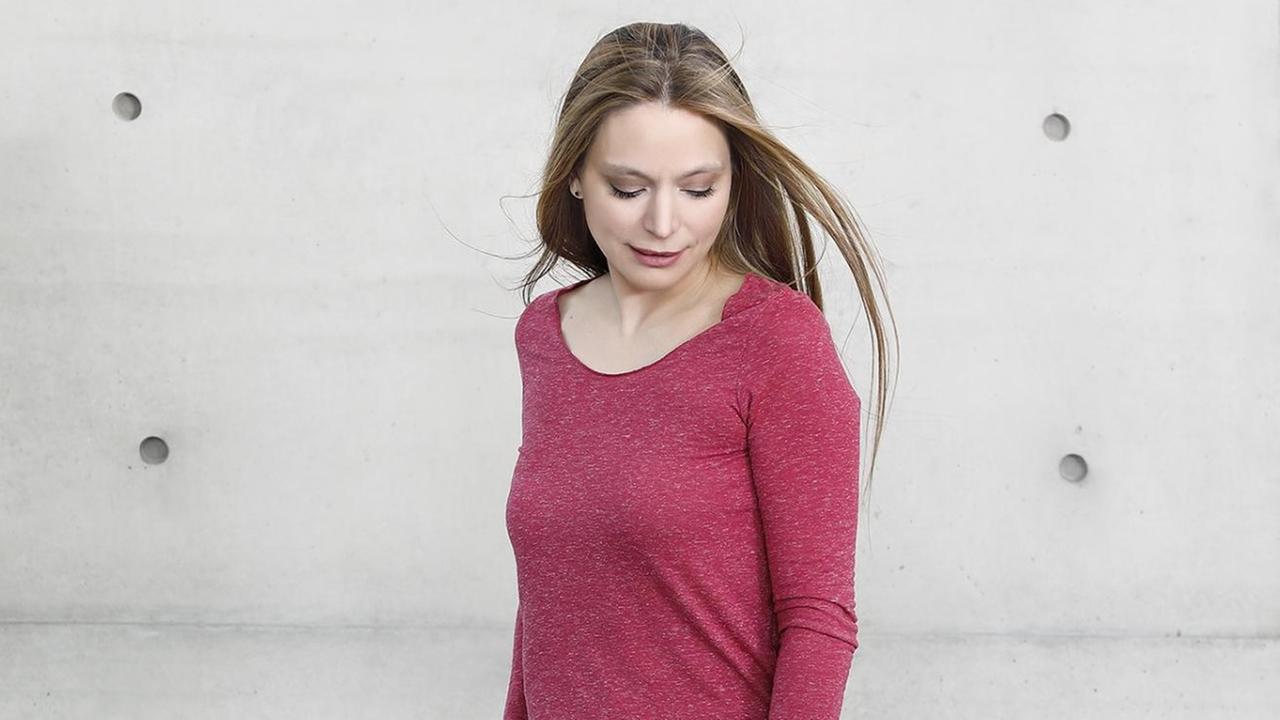 Geigerin steht im roten Pulli vor einer unverputzten Wand Geigerin steht im roten Pulli vor einer unverputzten Wand