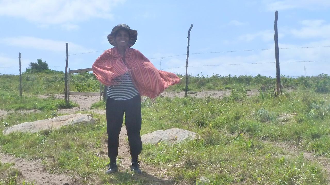 Pondoland-Aktivistin Nonhle Mbuthuma steht mit wehendem Schal vor einem Holzzaun Pondoland-Aktivistin Nonhle Mbuthuma steht mit wehendem Schal vor einem Holzzaun