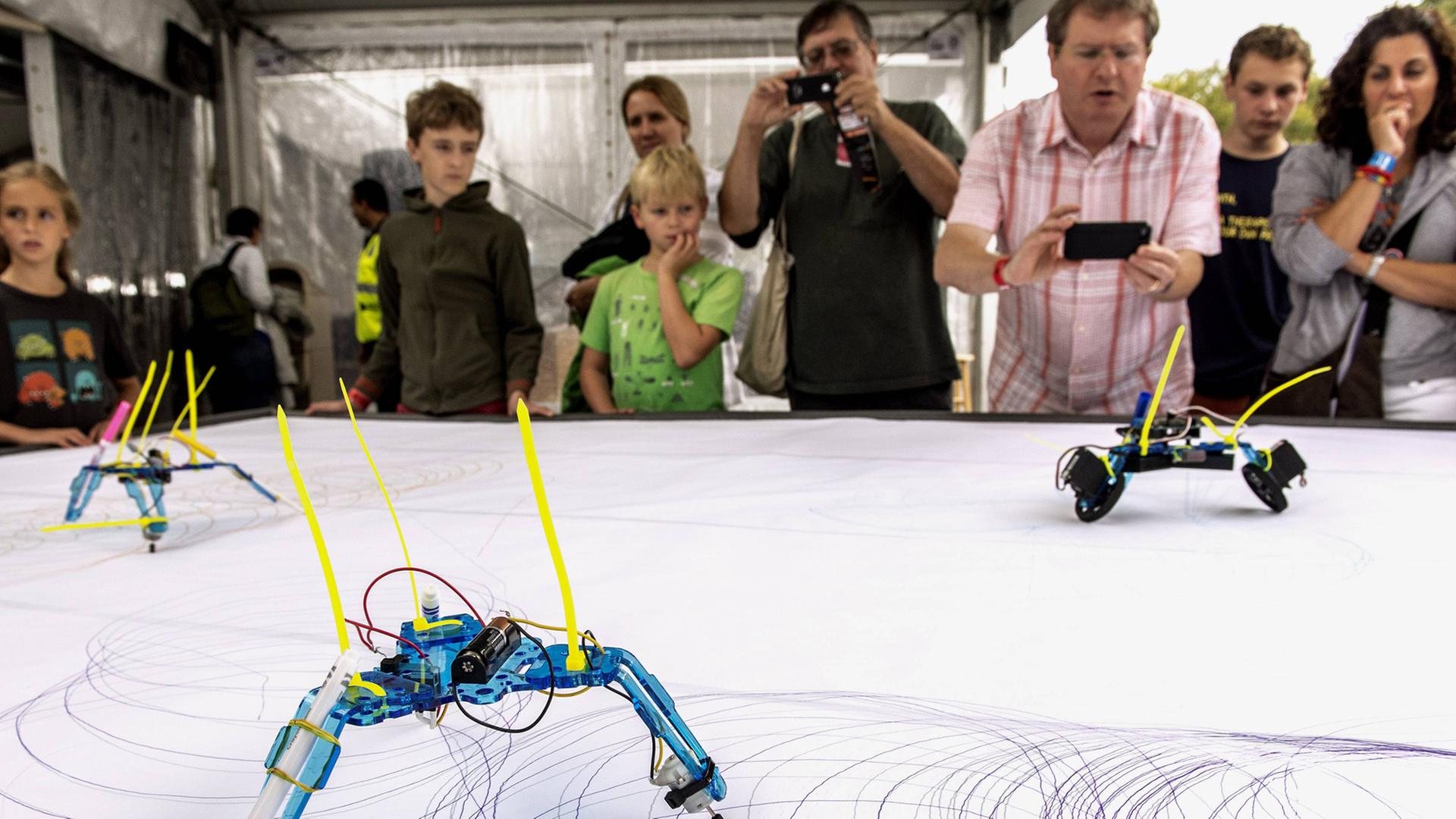 SYMBOLBILD - Besucher der "Word Maker Fair", einer zweitätigen Messe für Do-it-yourself-Innovationen, stehen im Jahr 2013 in New York an einem Tisch, auf dem Roboter zeichnen. SYMBOLBILD - Besucher der "Word Maker Fair", einer zweitätigen Messe für Do-it-yourself-Innovationen, stehen im Jahr 2013 in New York an einem Tisch, auf dem Roboter zeichnen.