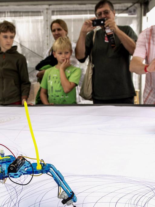 SYMBOLBILD - Besucher der "Word Maker Fair", einer zweitätigen Messe für Do-it-yourself-Innovationen, stehen im Jahr 2013 in New York an einem Tisch, auf dem Roboter zeichnen.
