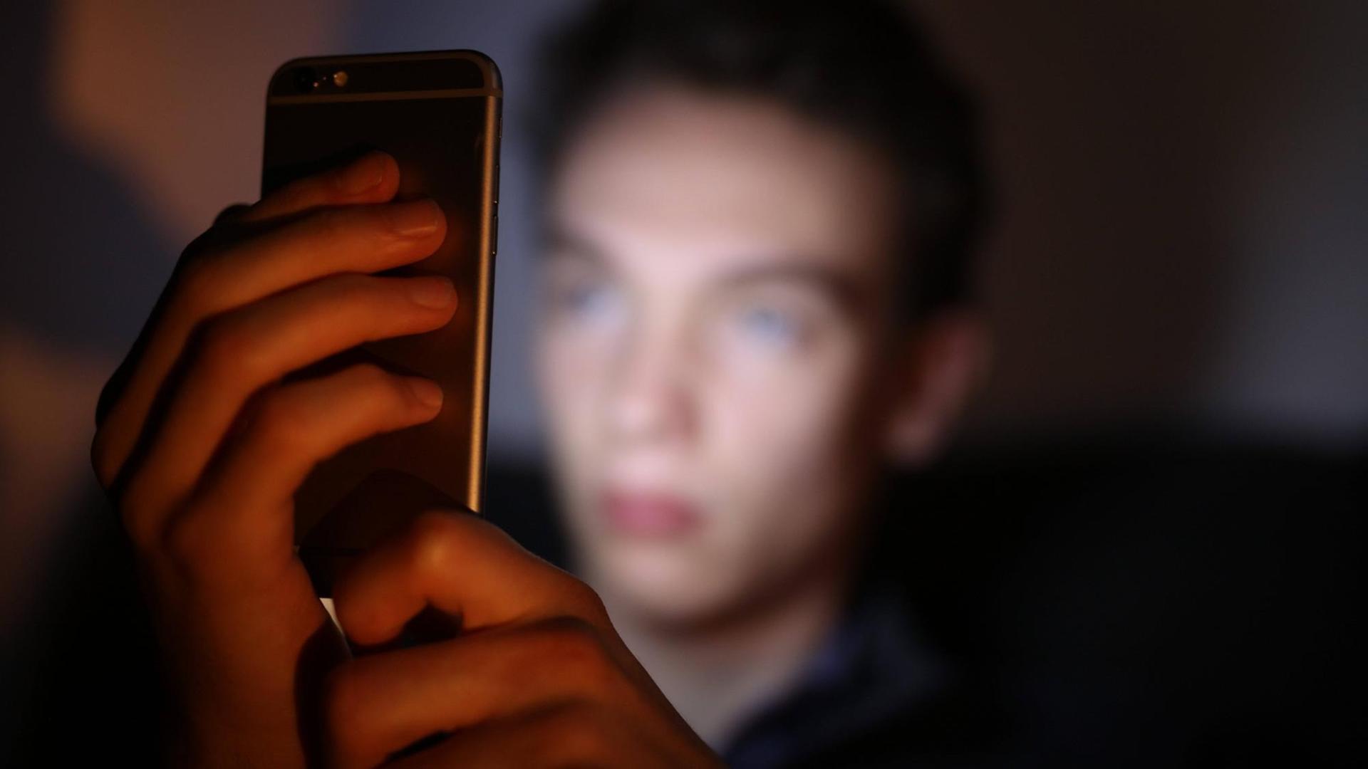 Ein Jugendlicher schaut auf sein Smartphone Ein Jugendlicher schaut auf sein Smartphone