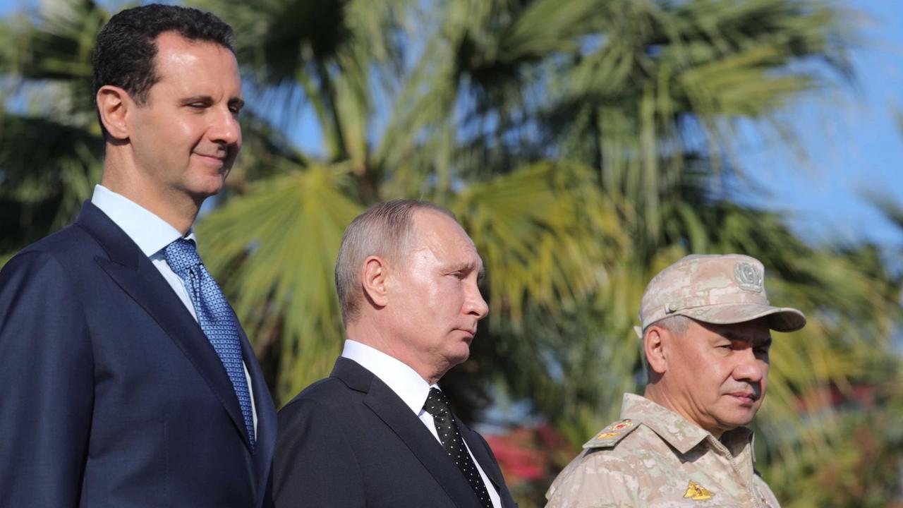 Syriens Präsident Baschar Al-Assad, Russlands Präsident Wladimir Putin und Russlands Verteidigungsminister Sergei Schoigu am 11. Dezember 2017 auf dem russischen Luftwaffenstützpunkt Hmeimim in Syrien