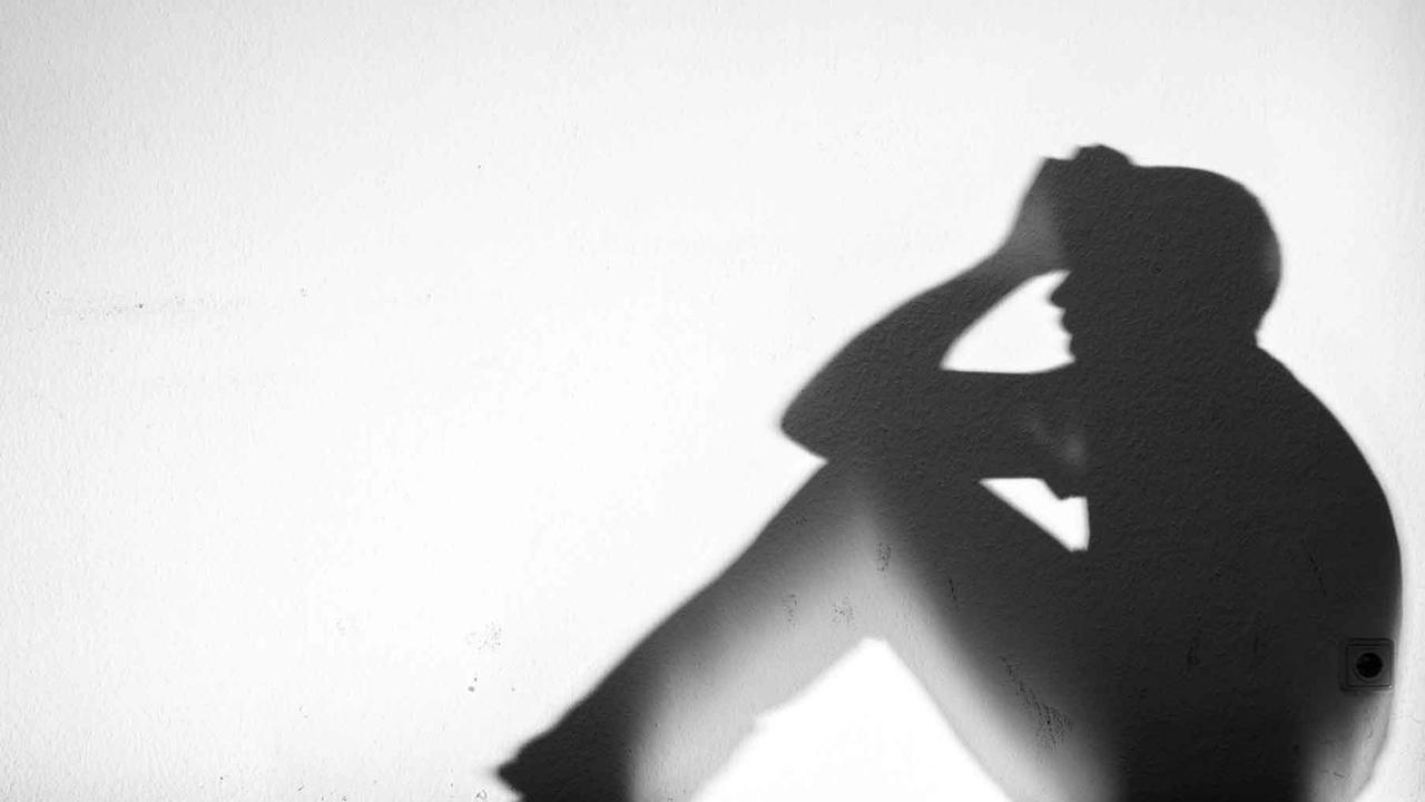 Ein Mensch sitzt auf einer Fensterbank und stützt seinen Kopf mit den Armen, im Gegenlicht sind nur seine Umrisse erkennbar. Ein Mensch sitzt auf einer Fensterbank und stützt seinen Kopf mit den Armen, im Gegenlicht sind nur seine Umrisse erkennbar.