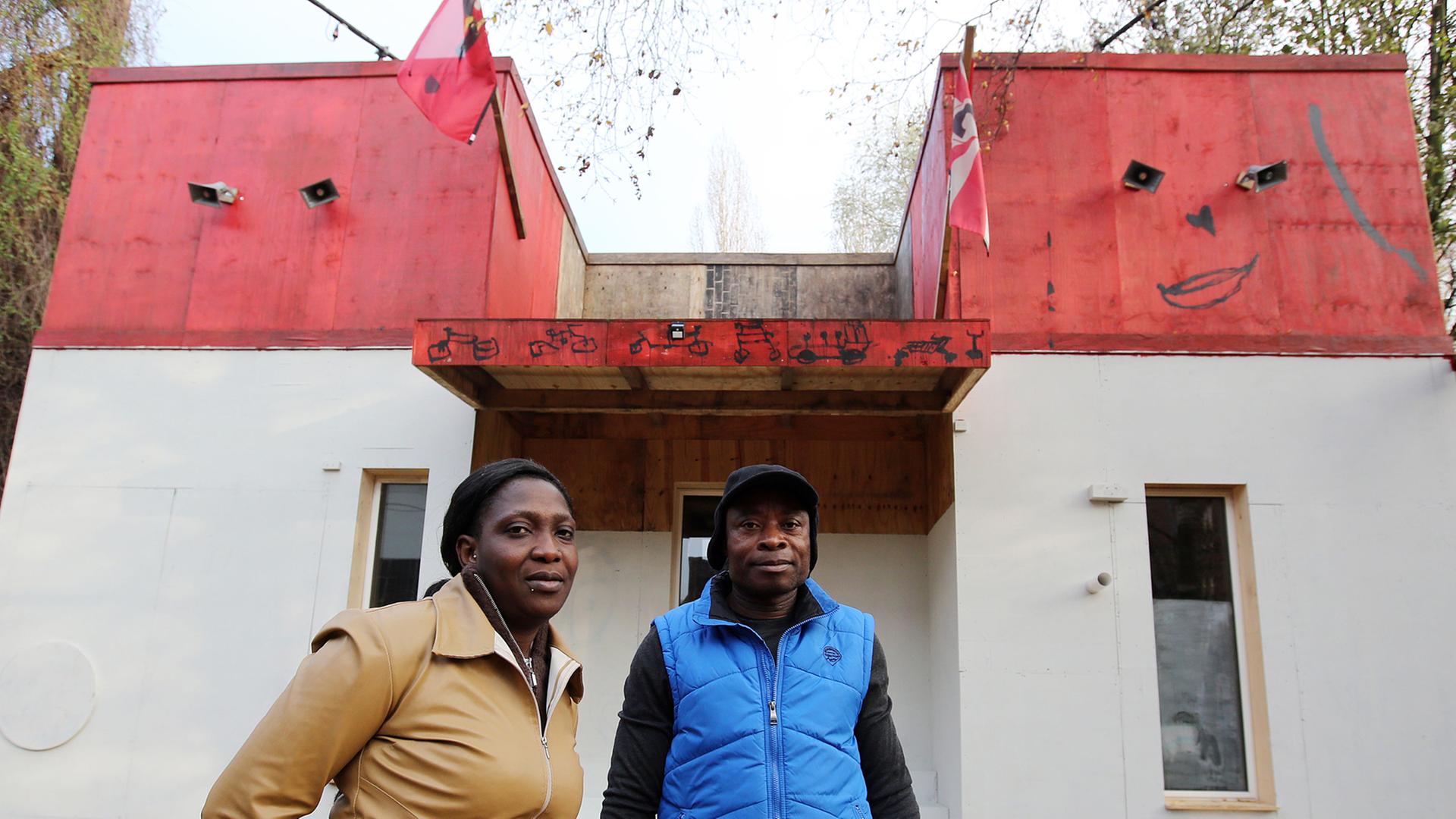 Der Sprecher der Lampedusa-Gruppe, Asuquo Udo, und Esther Olaide Olokodena, Mitglied der Gruppe, vor dem Kunstprojekt und Flüchtlingsquartier "Ecofavela" auf Kampnagel in Hamburg. Der Sprecher der Lampedusa-Gruppe, Asuquo Udo, und Esther Olaide Olokodena, Mitglied der Gruppe, vor dem Kunstprojekt und Flüchtlingsquartier "Ecofavela" auf Kampnagel in Hamburg.