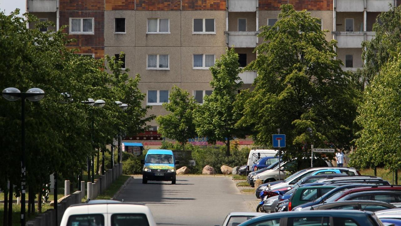 Eine Straße in einer Plattenbau-Siedlung. Am Straßenrand stehen Autos. Am Ende der Straße steht ein Plattenbau, der noch nicht renoviert ist. Eine Straße in einer Plattenbau-Siedlung. Am Straßenrand stehen Autos. Am Ende der Straße steht ein Plattenbau, der noch nicht renoviert ist.