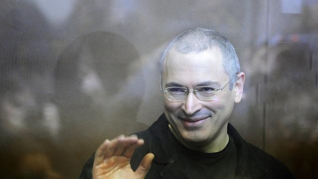 Kremlgegner Michail Chodorkowski steht während eines Prozesses im Gerichtssaal und winkt.