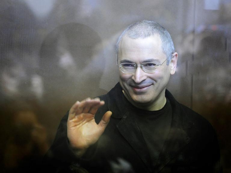 Kremlgegner Michail Chodorkowski steht während eines Prozesses im Gerichtssaal und winkt.