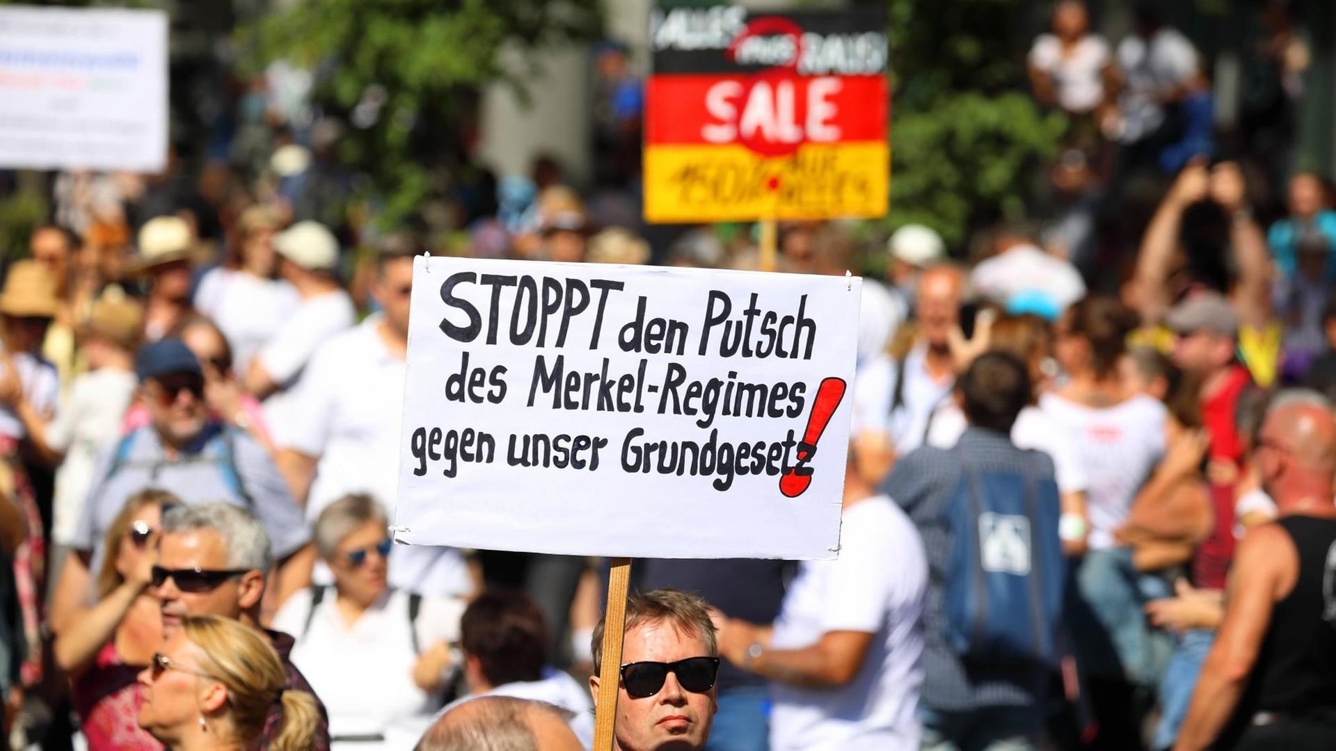 Ohne Maske und mit Anti-Merkel-Transparent demonstrieren Menschen in Berlin gegen die Anti-Corona-Maßnahmen. Ohne Maske und mit Anti-Merkel-Transparent demonstrieren Menschen in Berlin gegen die Anti-Corona-Maßnahmen.