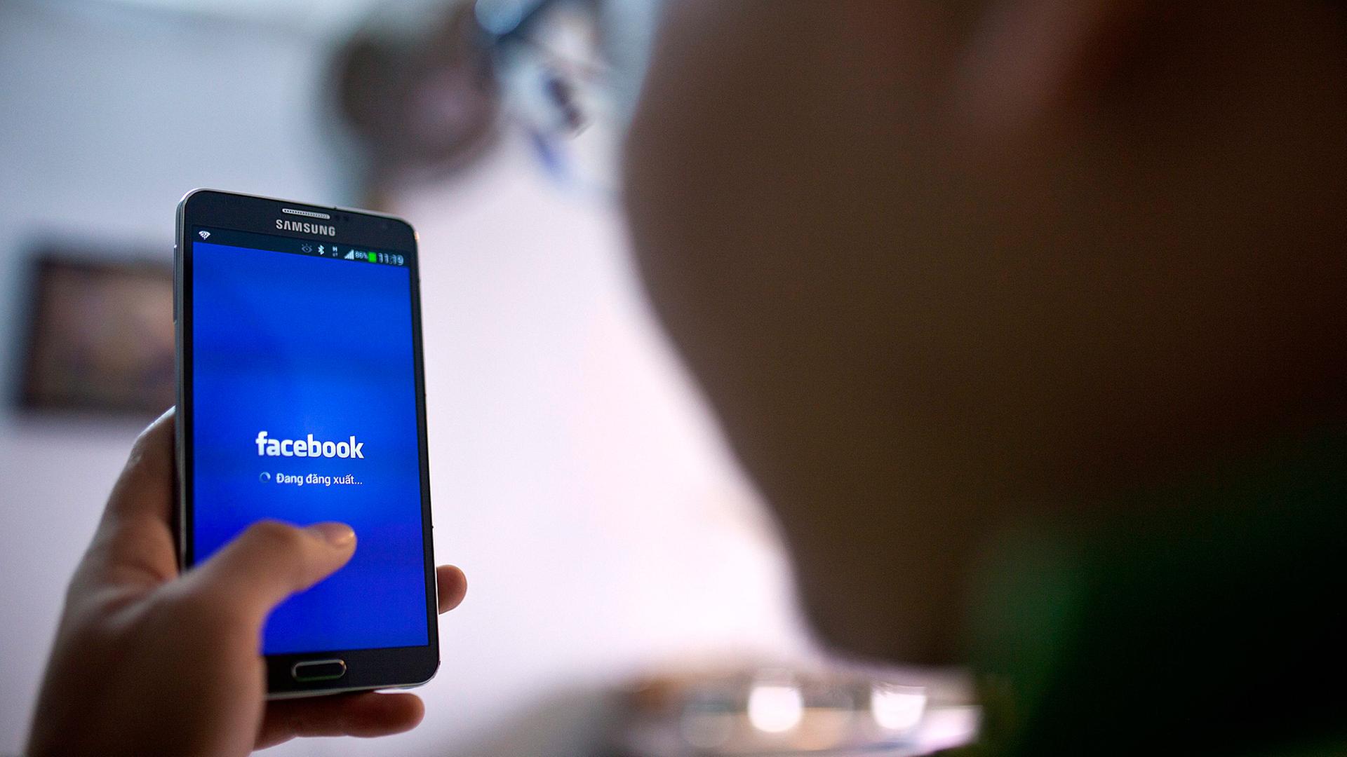Ein Mann postet per Smartphone auf Facebook. Ein Mann postet per Smartphone auf Facebook.