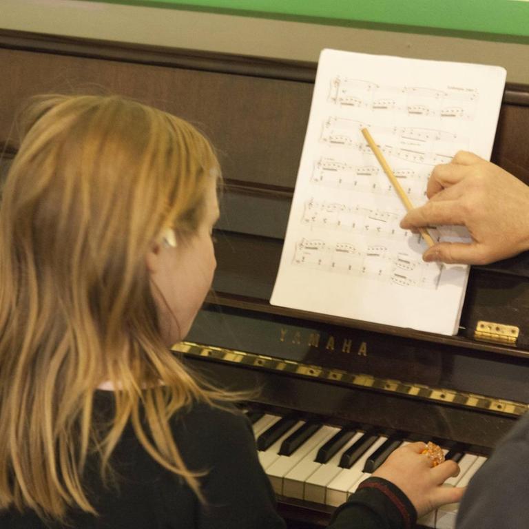 Ein Mädchen beim Klavierunterricht