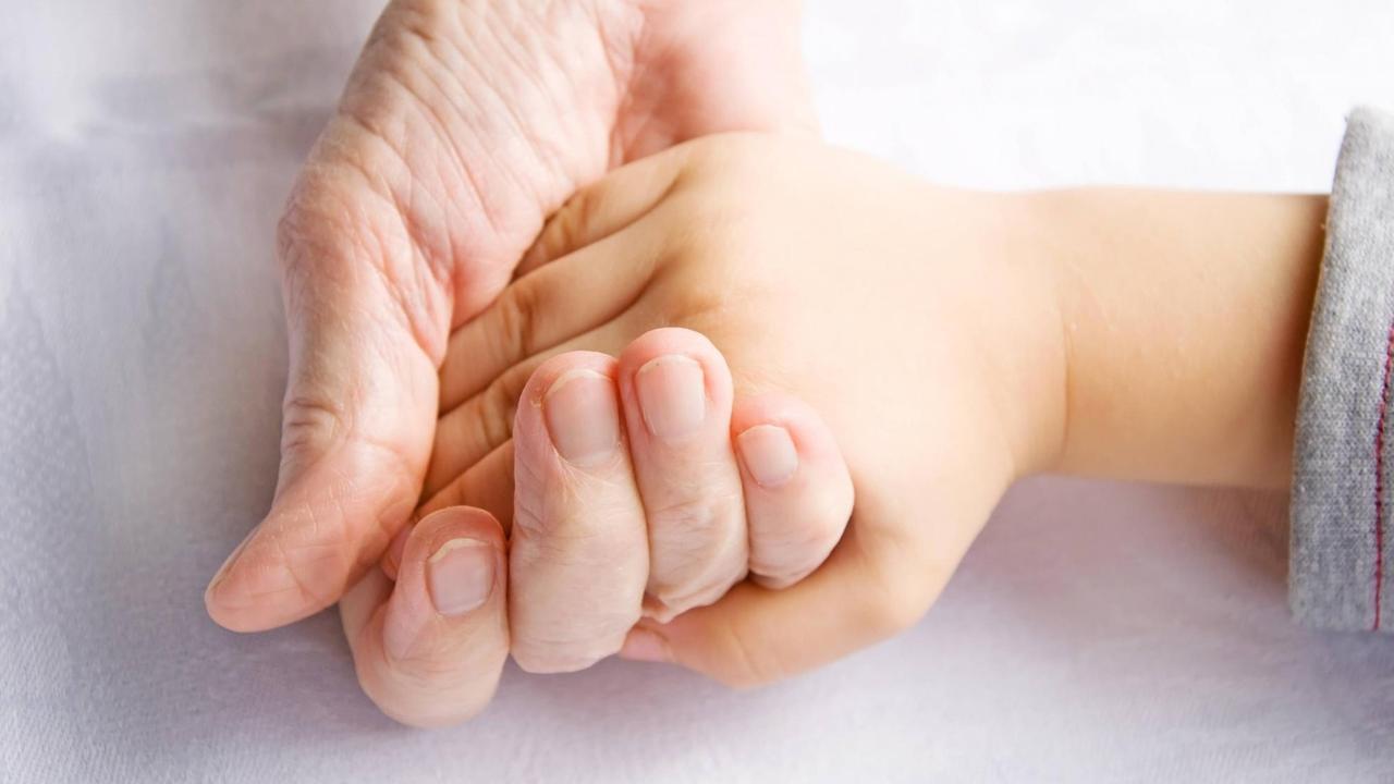 Eine ältere Hand hält eine Kinderhand. Eine ältere Hand hält eine Kinderhand.
