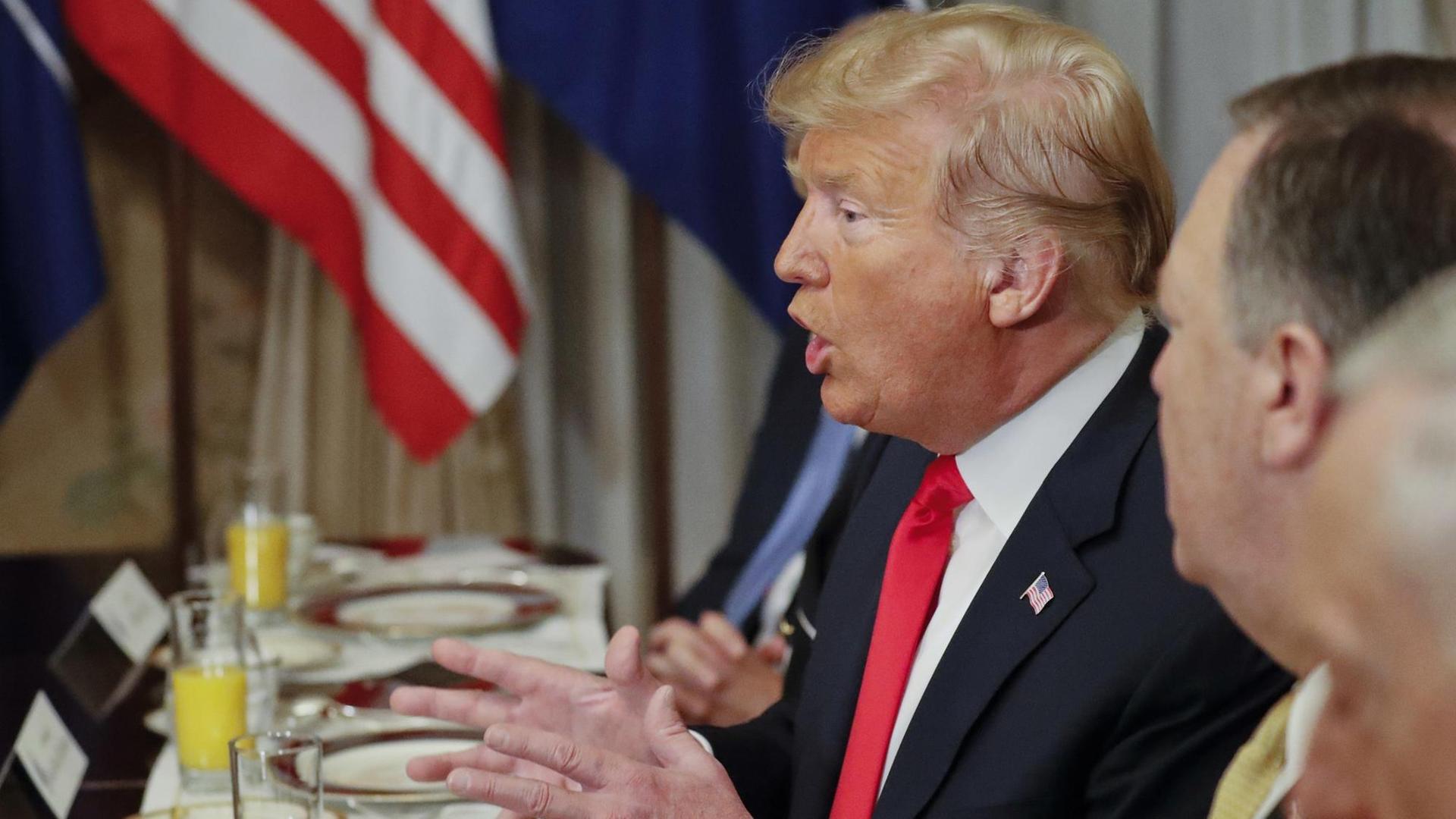 Der Präsident ist von der Seite fotografiert. Er sitzt gestikulierend an einem Tisch vor seinem Teller und sagt etwas. Neben ihm unscharf US-Außenminister Pompeo.