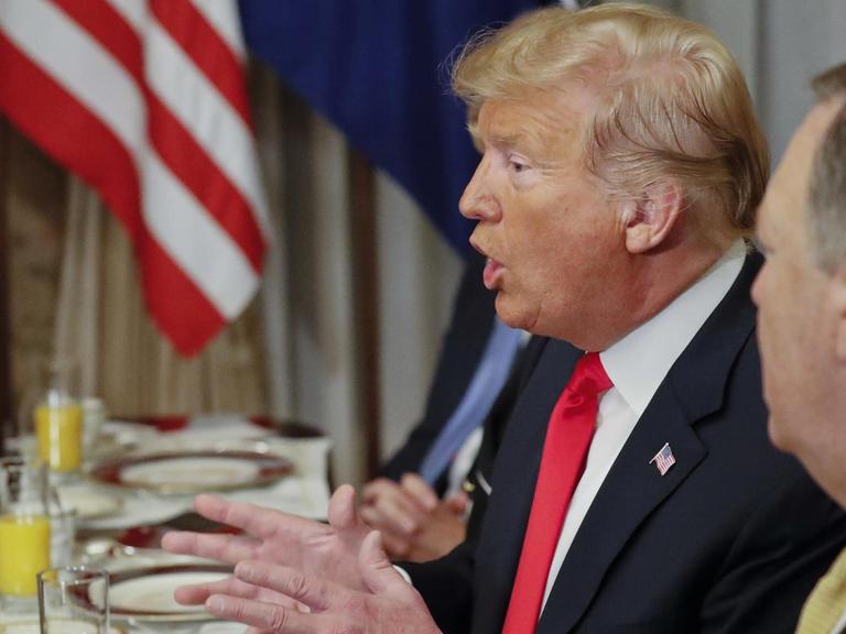 Der Präsident ist von der Seite fotografiert. Er sitzt gestikulierend an einem Tisch vor seinem Teller und sagt etwas. Neben ihm unscharf US-Außenminister Pompeo.