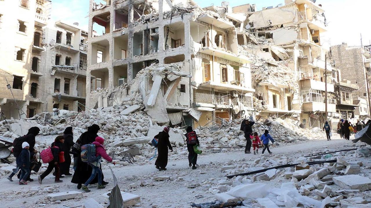 Syrische Familien auf der Flucht aus Ost-Aleppo - im Hintergrund sind zerstörte Gebäude zu sehen. Syrische Familien auf der Flucht aus Ost-Aleppo - im Hintergrund sind zerstörte Gebäude zu sehen.