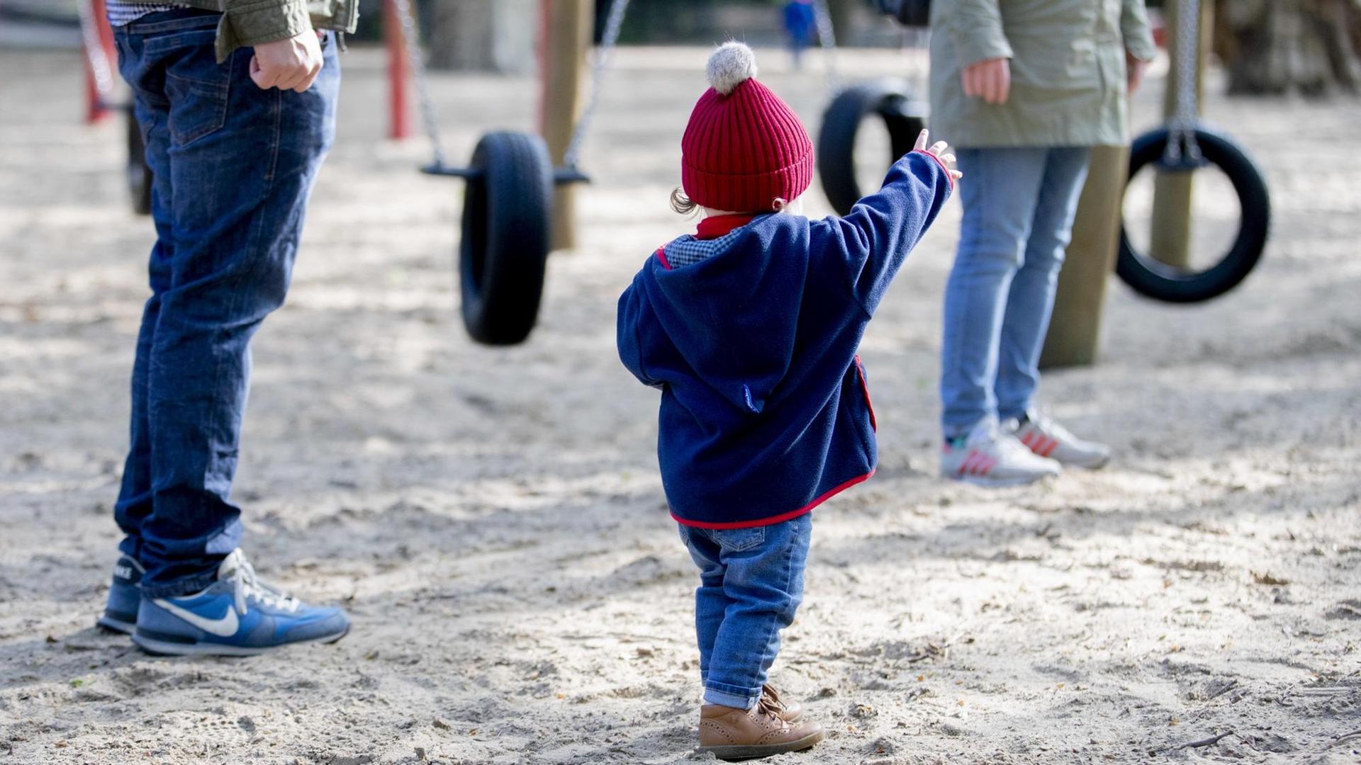 02.05.2020, Berlin: Ein Kind steht mit seinen Eltern auf einem Spielplatz im Volkspark Wilmersdorf. Nachdem Spielplätze zur Eindämmung des Coronavirus geschlossen waren, öffnen diese nun wieder. Foto: Christoph Soeder/dpa - ACHTUNG: Nur zur redaktionellen Verwendung im Zusammenhang mit der aktuellen Berichterstattung und nur mit vollständiger Nennung des vorstehenden Credits | Verwendung weltweit 02.05.2020, Berlin: Ein Kind steht mit seinen Eltern auf einem Spielplatz im Volkspark Wilmersdorf. Nachdem Spielplätze zur Eindämmung des Coronavirus geschlossen waren, öffnen diese nun wieder. Foto: Christoph Soeder/dpa - ACHTUNG: Nur zur redaktionellen Verwendung im Zusammenhang mit der aktuellen Berichterstattung und nur mit vollständiger Nennung des vorstehenden Credits | Verwendung weltweit