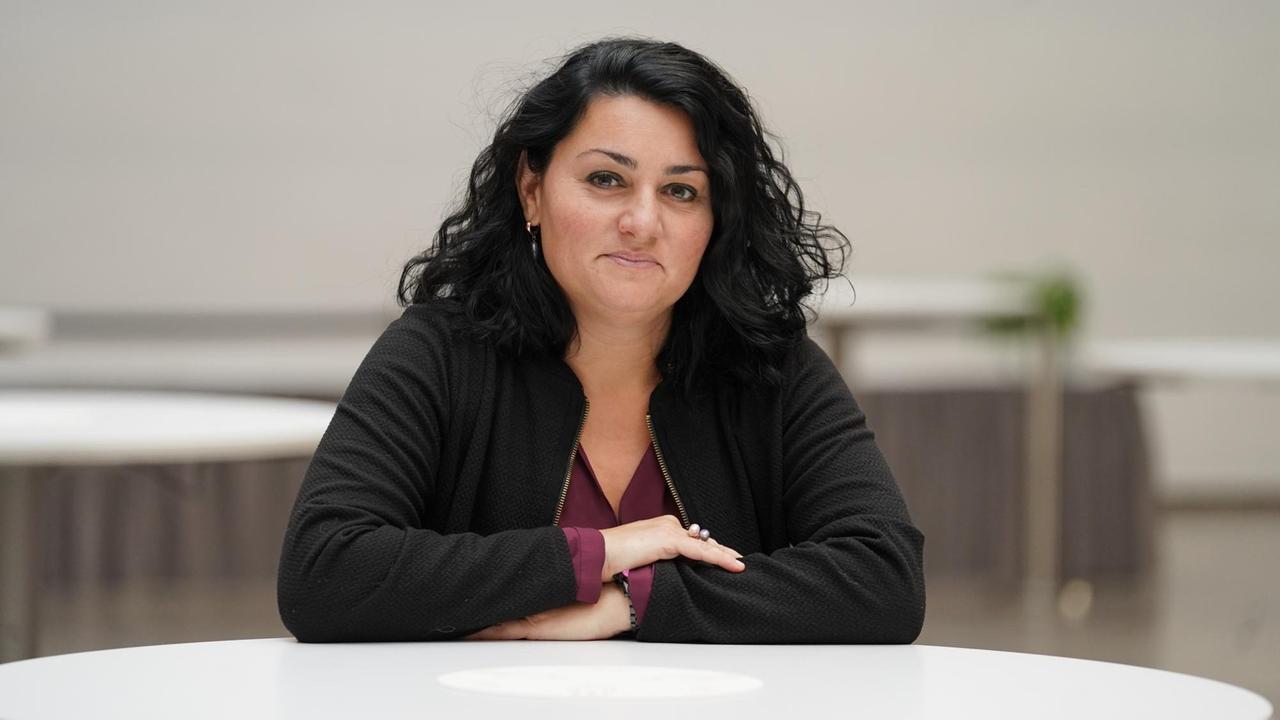 Lamya Kaddor, Islamwissenschaftlerin und Publizistin von der Universität Duisburg-Essen, sitzt an einem Tisch und schaut in die Kamera. 