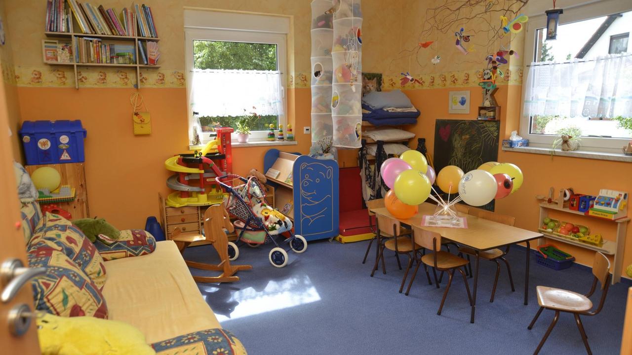 In einem Zimmer zur Kinder-Tagespflege stehen Spielzeuge, ein Tisch und Stühle.
