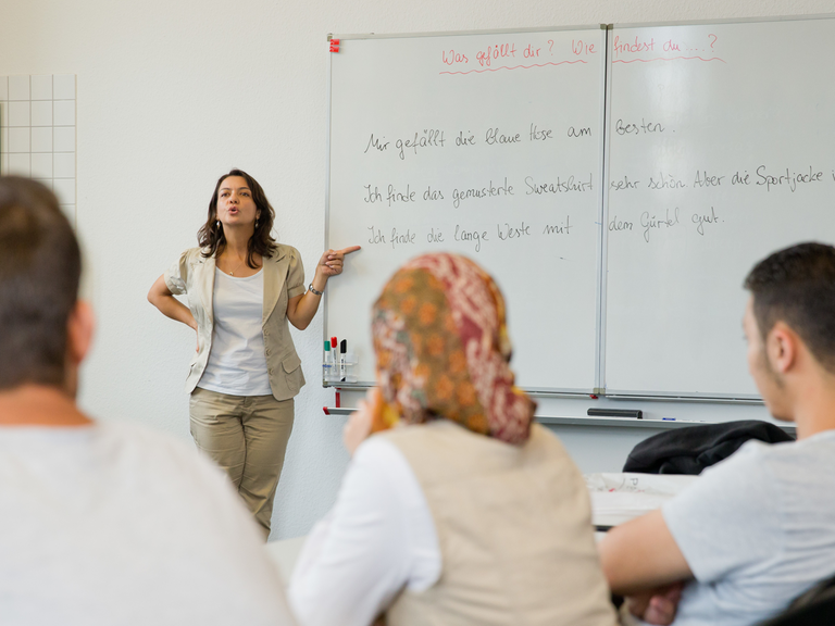 Die Deutschlehrerin Gülsen Landshuter geht mit Teilnehmern eines Integrationskurses im Bildungszentrum in Nürnberg eine Sprachübung durch.