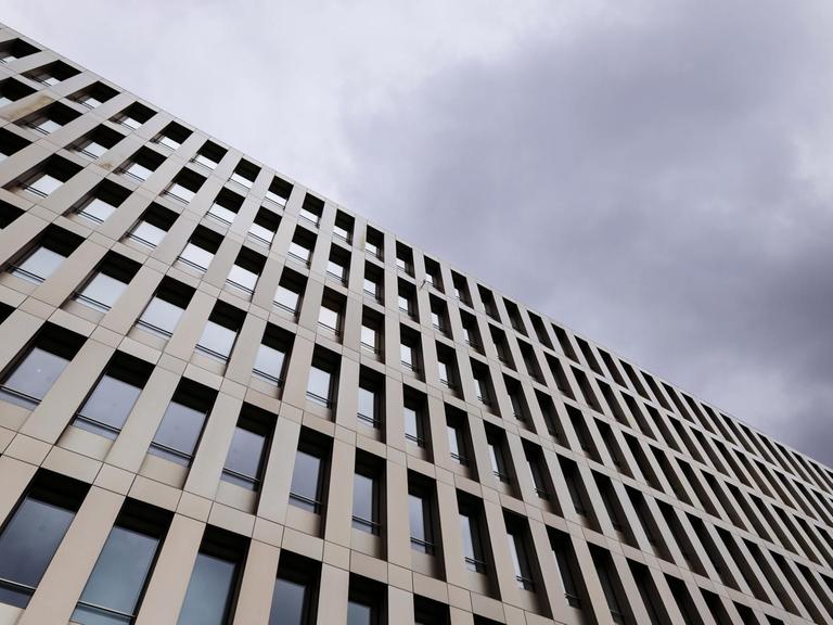 Schräg von unten erhebt sich das Gebäude des BND gegen einen dramatisch bewölkten Himmel.