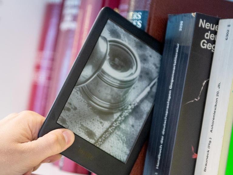 Ein Mann entnimmt ein E-Book-Reader aus einem Bücherregal.