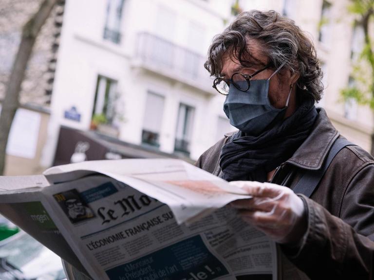 Ein Mann mir Mundschutz liest die Zeitung "Le Monde" in Paris.