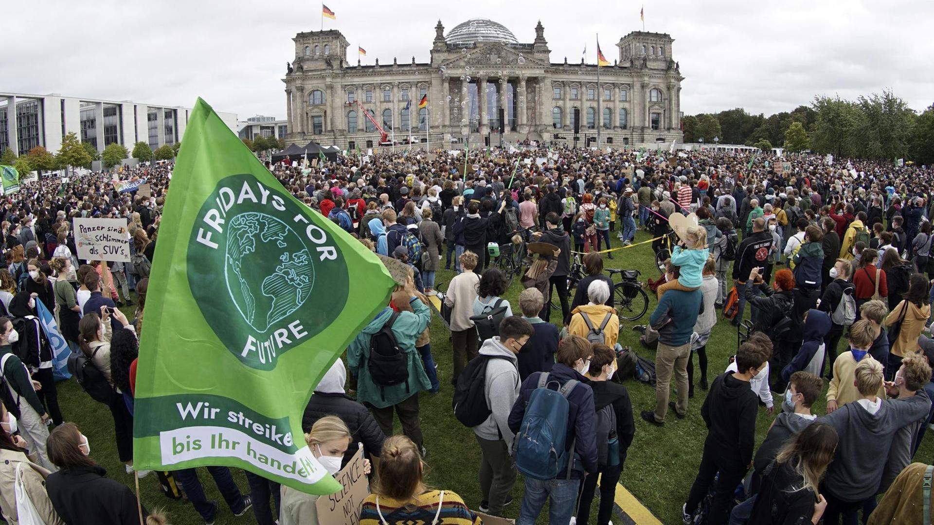 Demonstrantinnen und Demonstranten stehen vor dem Bundestag. Auf einer Fahne steht Fridays for Future. Demonstrantinnen und Demonstranten stehen vor dem Bundestag. Auf einer Fahne steht Fridays for Future.
