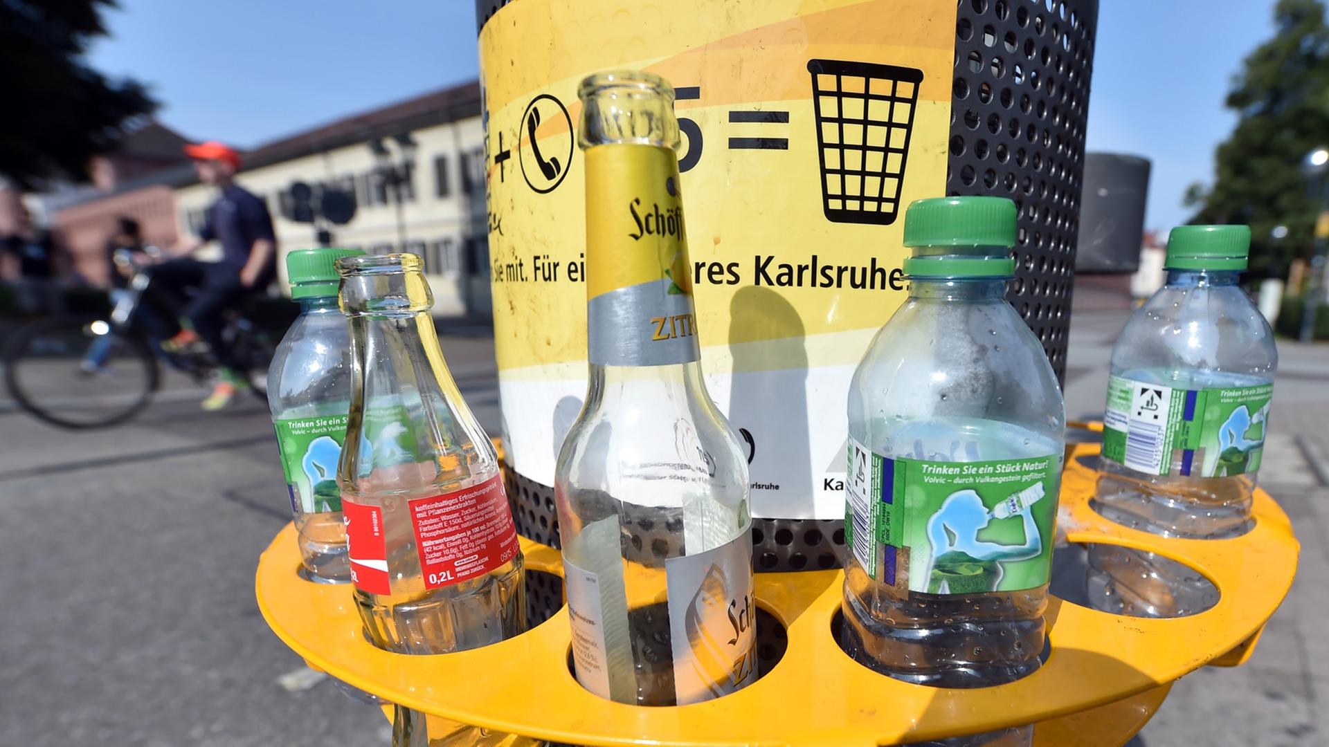 An einem Mülleimer in der Innenstadt von Karlsruhe (Baden-Württemberg) ist am 06.08.2014 ein Pfandring angebracht in dem leere Flaschen stehen. Wer seine Pfandflaschen oder -dosen nicht ins Geschäft zurückbringen möchte, kann sie in die Ringe stecken. So ist es Pfandsammlern einfacher möglich, die Flaschen und Dosen mitzunehmen. An einem Mülleimer in der Innenstadt von Karlsruhe (Baden-Württemberg) ist am 06.08.2014 ein Pfandring angebracht in dem leere Flaschen stehen. Wer seine Pfandflaschen oder -dosen nicht ins Geschäft zurückbringen möchte, kann sie in die Ringe stecken. So ist es Pfandsammlern einfacher möglich, die Flaschen und Dosen mitzunehmen.