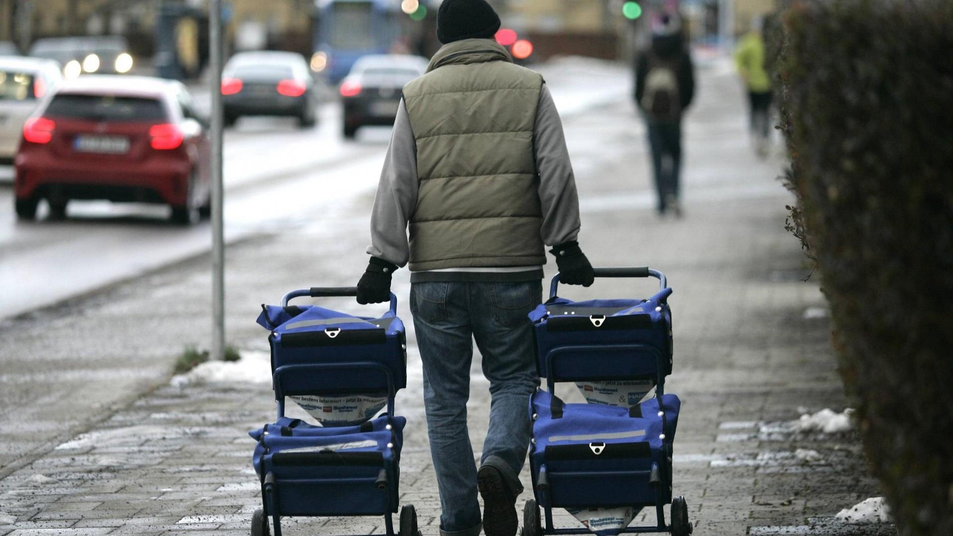 Ein Zeitungszusteller zieht zwei Zeitungswagen hinter sich her. Ein Zeitungszusteller zieht zwei Zeitungswagen hinter sich her.