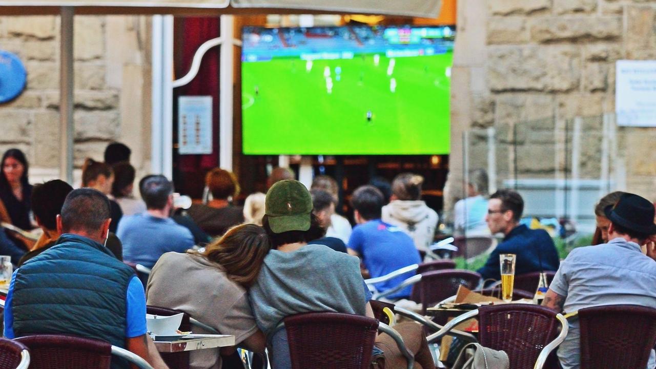 Fußballfans sitzen in einem Café. Sie schauen ein EM-Spiel von der deutschen Mannschaft Fußballfans sitzen in einem Café. Sie schauen ein EM-Spiel von der deutschen Mannschaft