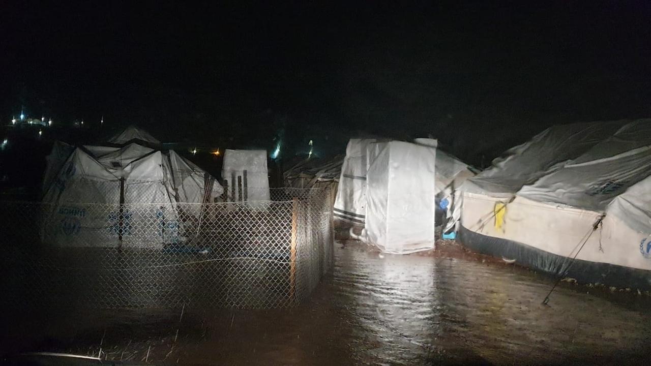 Weiße Zelte stehen nachts bei Regen tief im Wasser. Weiße Zelte stehen nachts bei Regen tief im Wasser.