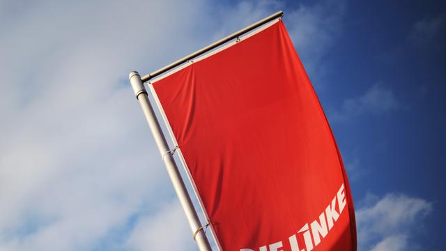 Eine Fahne der Linkspartei weht vor einem blauen Himmel.