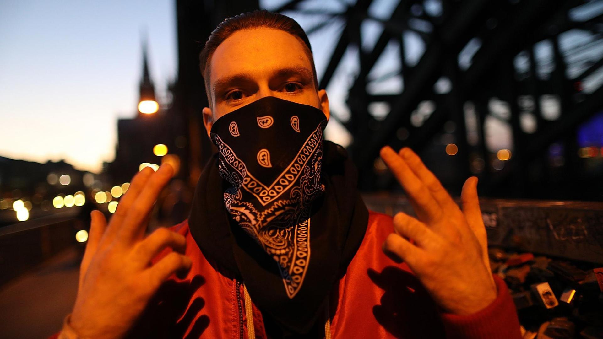 Der Rapper Spongebozz alias Sun Diego (bürgerlicher Name: Dimitri Aleksandrovic Chpakov) streckt die ersten drei Finger beider Hände nach oben.