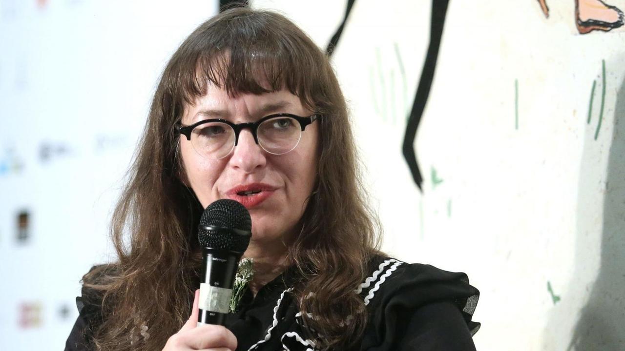 Comiczeichnerin Ulli Lust sitzt auf eine Podium. Eine Frau mit langen dunklen Haaren und einer Brille.