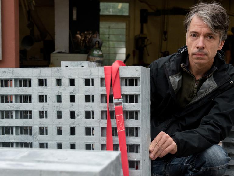 Der Künstler Markus Draper neben Plattenbau-Modellen: In Görlitz ist bis zum 31. Januar 2016 seine Ausstellung "Inge zu Fuß zur Arbeit" zu sehen, eine Reflexion des Künstlers über Alltag in der DDR in den 1980er Jahren.