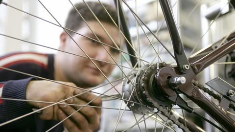 Ein junger Mann kontrolliert die Radaufhängung eines Fahrrads.