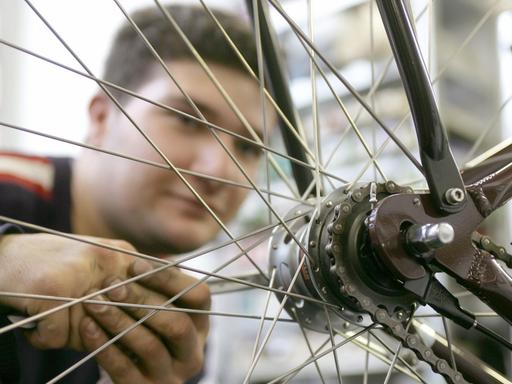 Ein junger Mann kontrolliert die Radaufhängung eines Fahrrads.