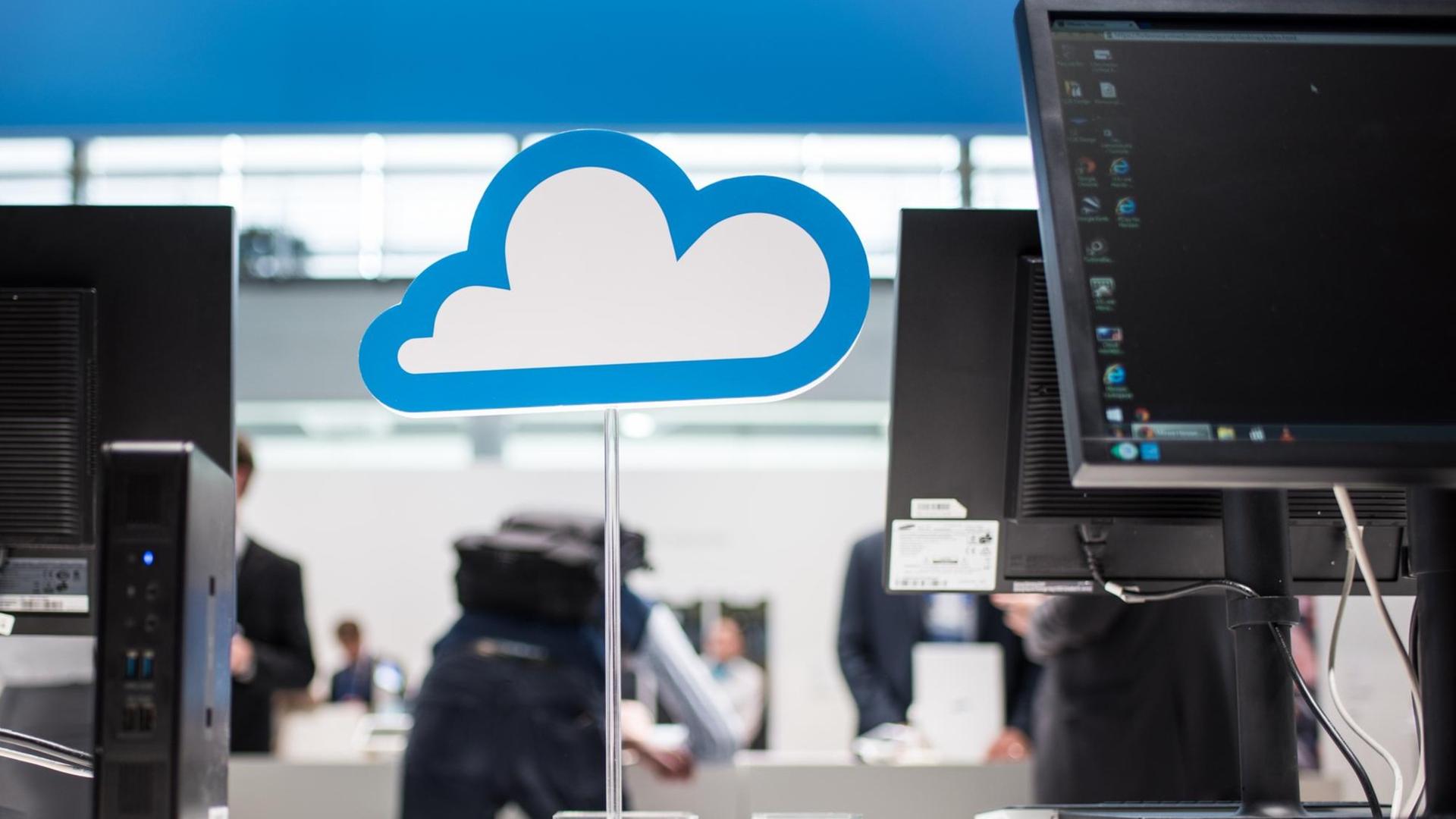 Eine Pappwolke auf einem Ständer als Symbol für Cloudcomputing steht neben Computermonitoren.