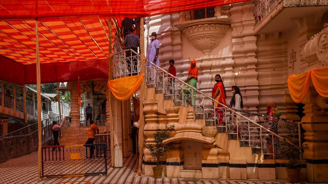 Menschen mit Mundschutz stehen in einer Warteschlange auf den Stufen zum Kalkaji-Tempel in Neu-Delhi.